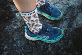 Feet in patterned trail socks and blue trail shoes on a rock