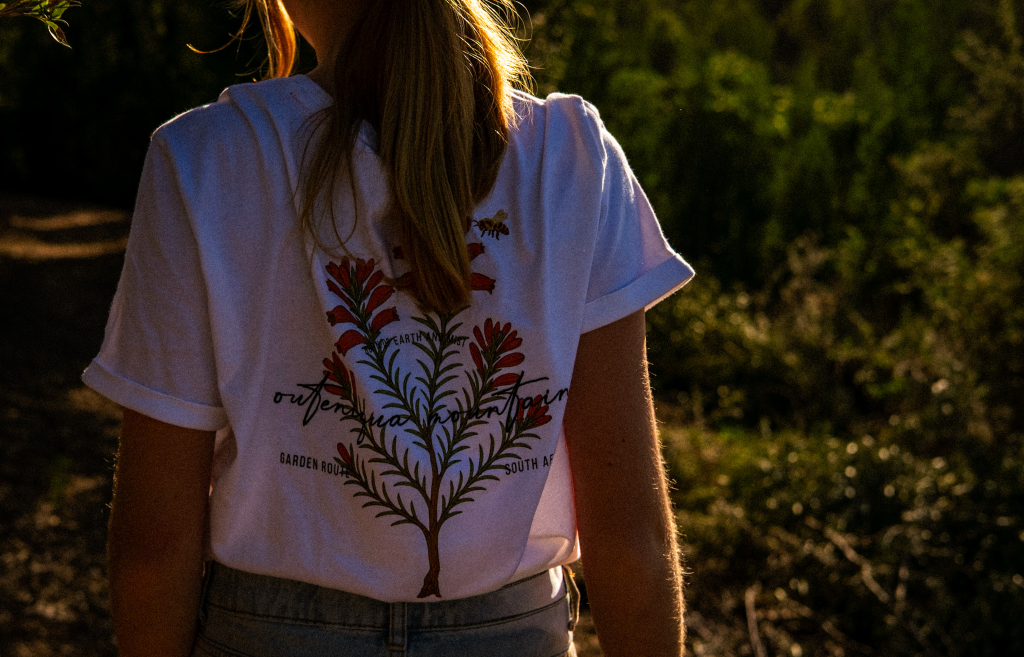 Woman wearing a white tee with a botanical print on the back