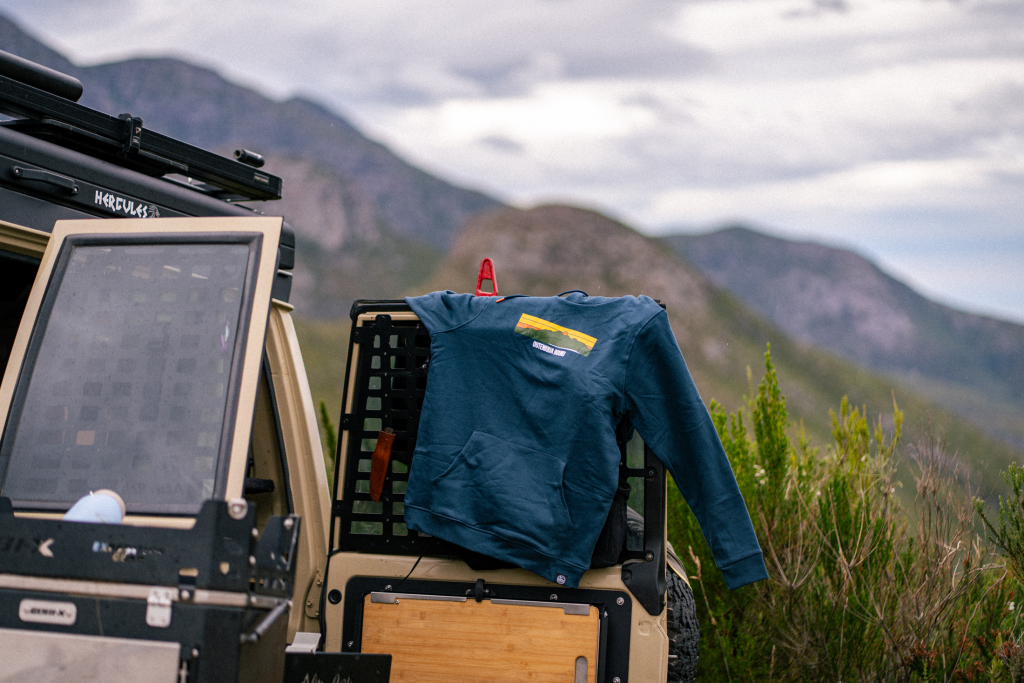 Outdoor gear and a warm layer packed in an overland vehicle with mountain views
