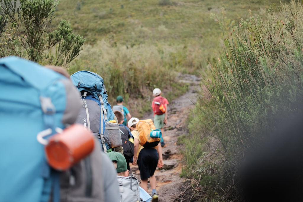 Hikers with backpacks on a narrow fynbos trail