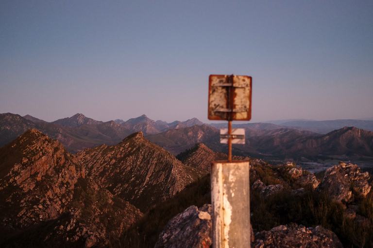 Summit marker post on a mountain peak at sunrise