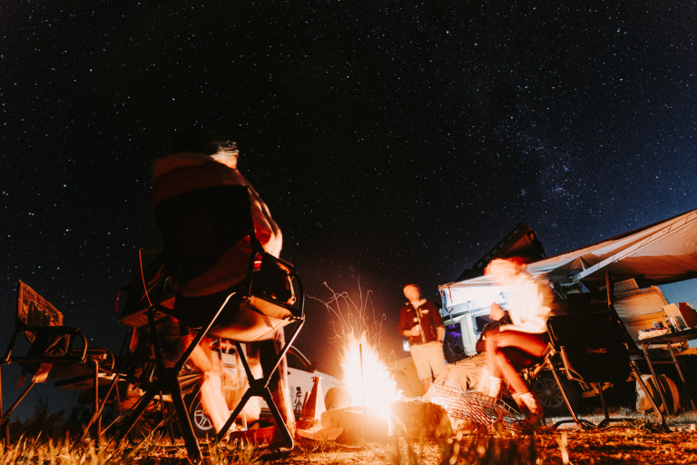 Friends gathered around a campfire under the night sky