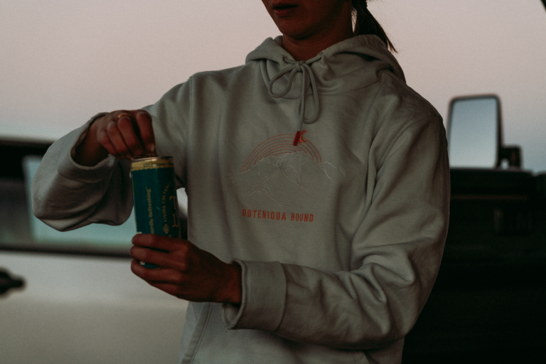 Woman in a cream Ladies Moonrise Hoodie by an overland vehicle