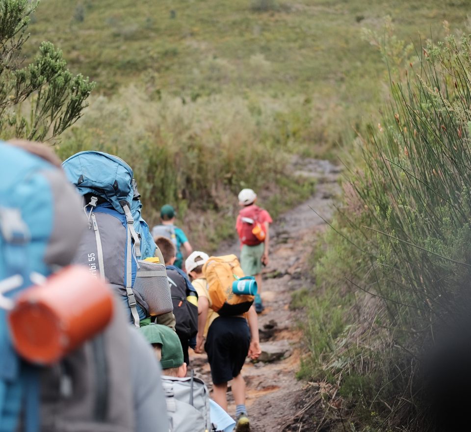 Hikers with backpacks on a narrow fynbos trail