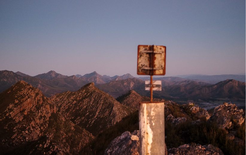 Summit marker post on a mountain peak at sunrise