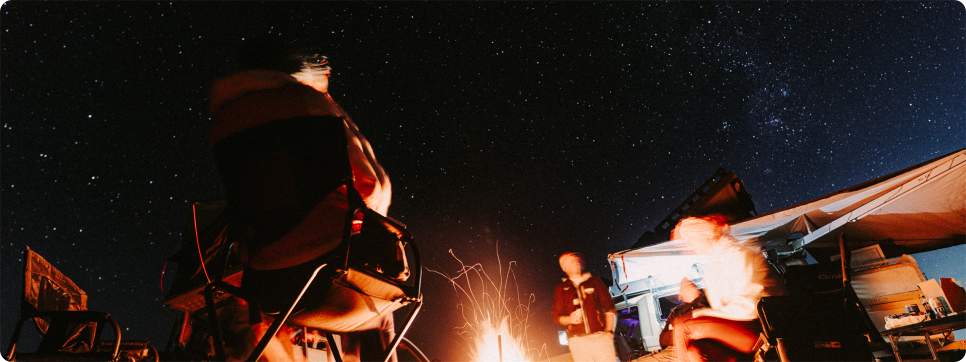 Friends gathered around a campfire under the night sky
