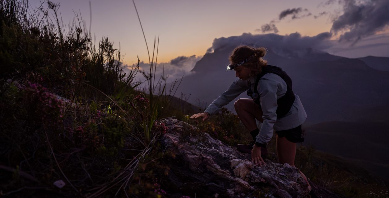 Hiker scrambling over rocks on a mountain at dusk